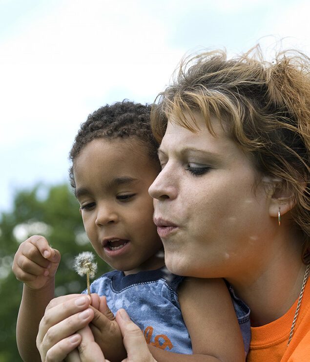 Woman with toddler playing with a dandelion