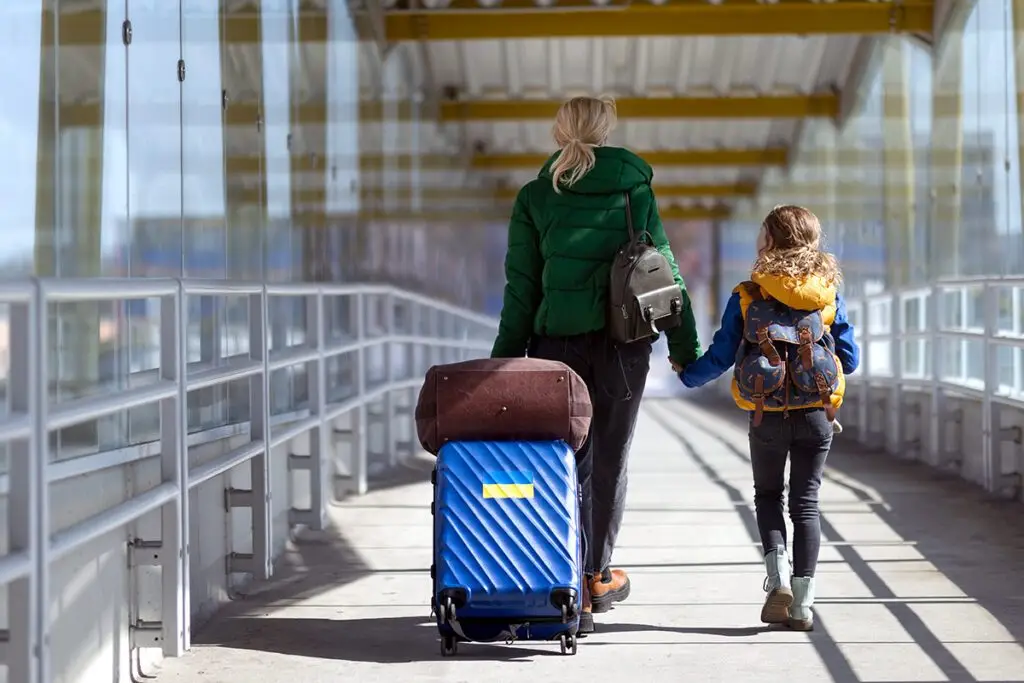 Rear view of Ukrainian immigrant mother with child with luggage